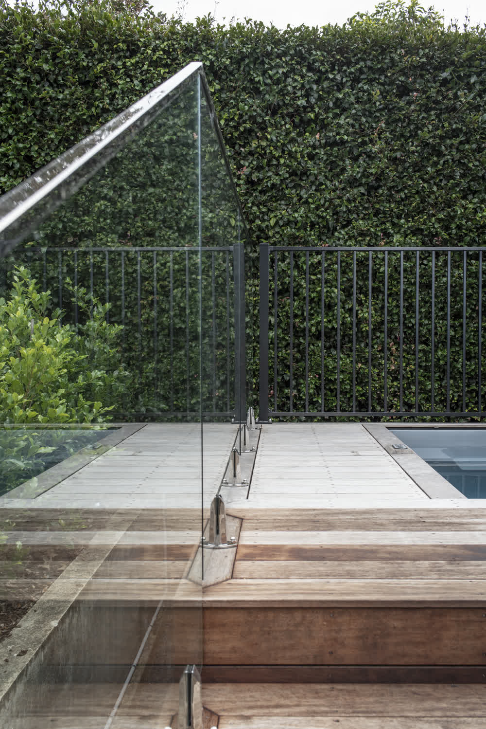 Pool area in decked area with glass balustrade and fencing around